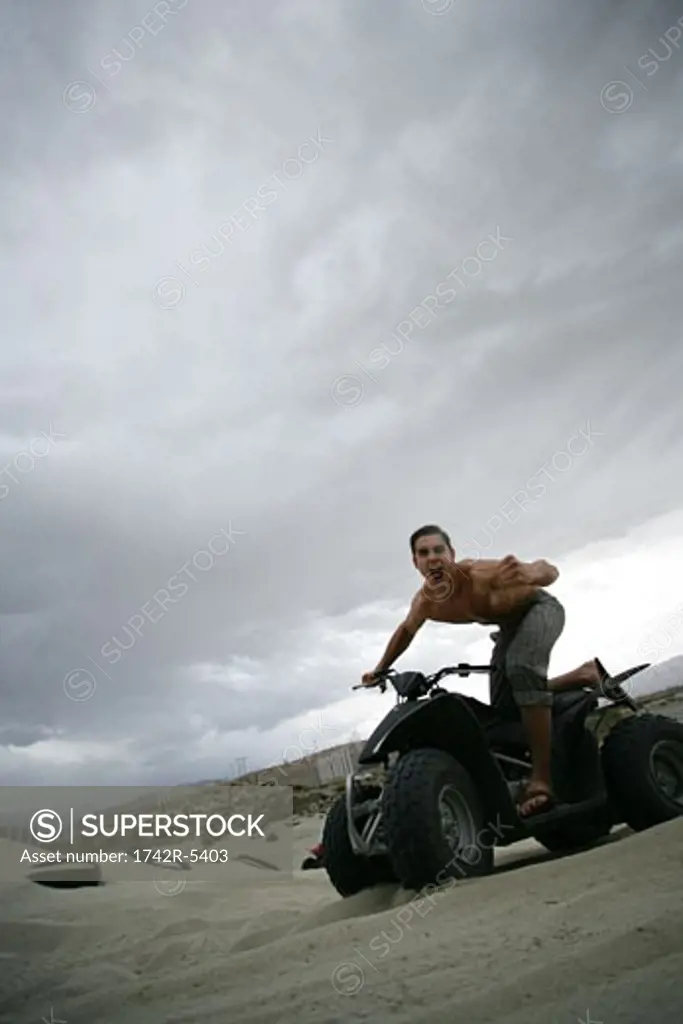 Excited man riding ATV in desert