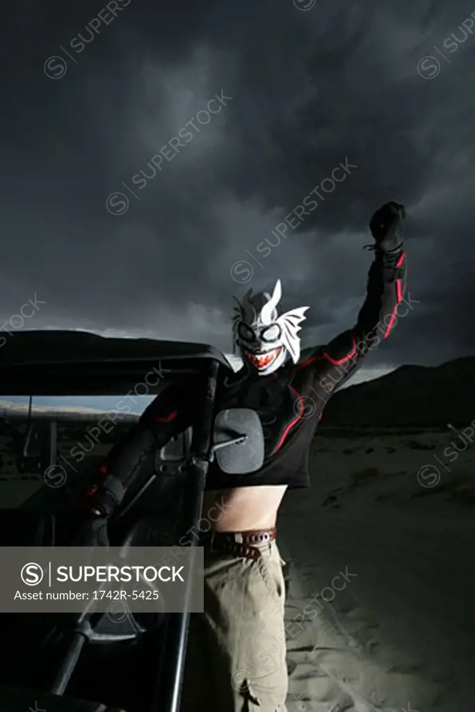 Man wearing mask standing in desert with jeep
