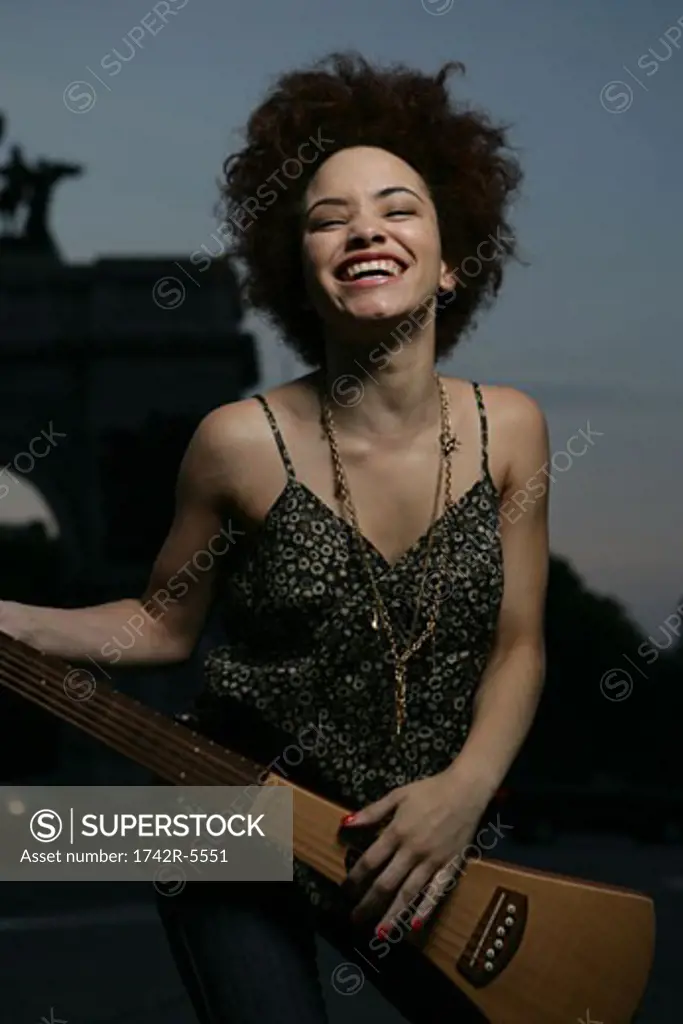 african american female playing travel guitar outside