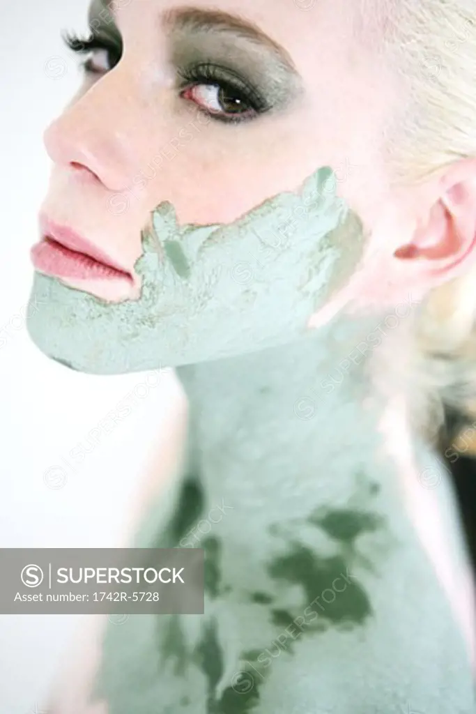 Close-up of a woman wearing a green mask on her face, neck and shoulders