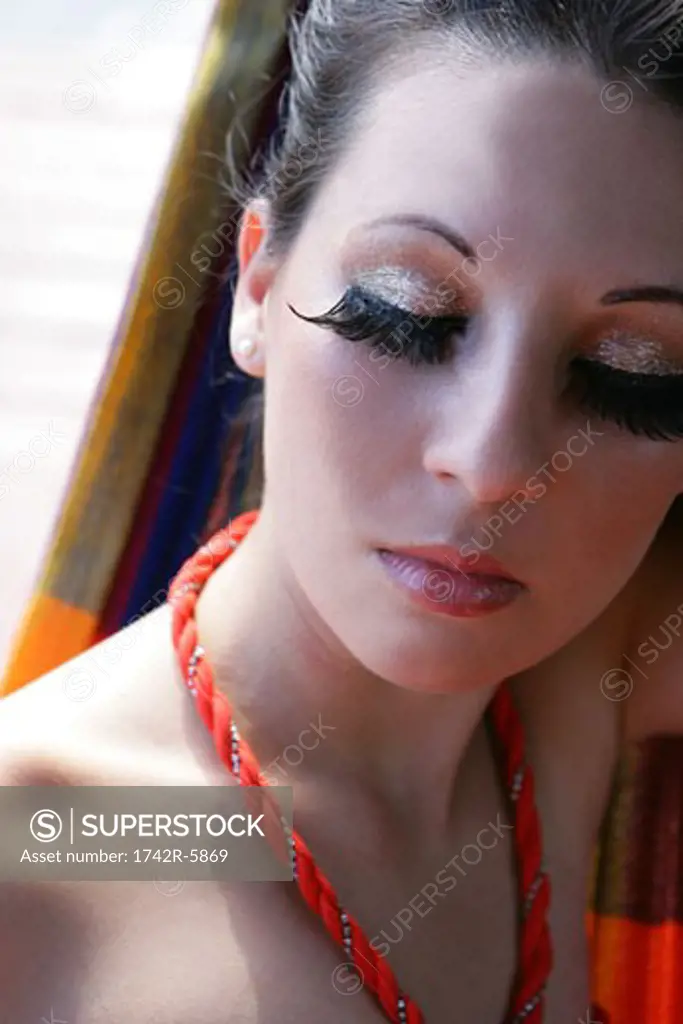 Woman facing camera, eyes closed wearing false eyelashes