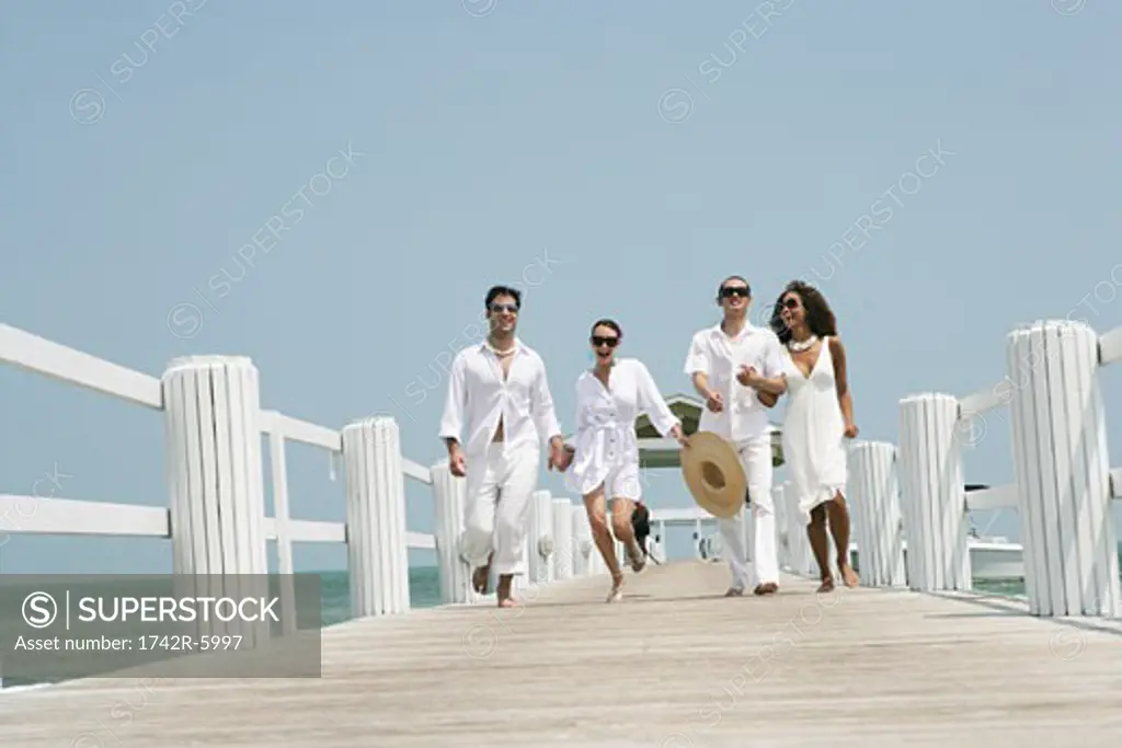Young happy couples running on pier.