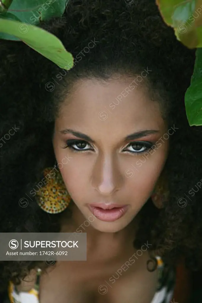 Close-up of young woman in tropical leaves.