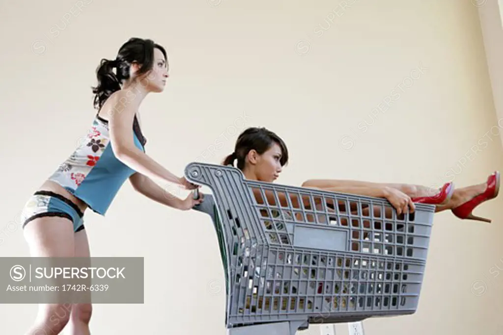 Woman pushing another woman in a shopping cart