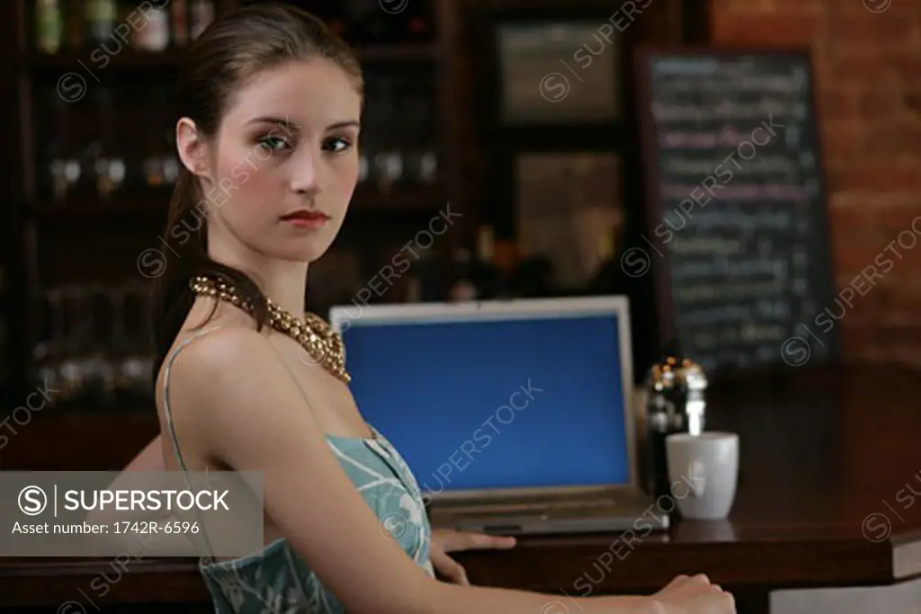 Young woman sitting at bar with laptop.