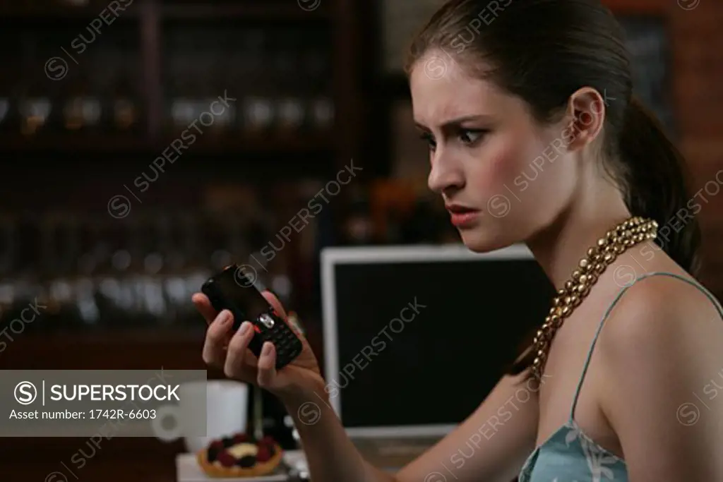 Confused woman looking at phone in cafe.