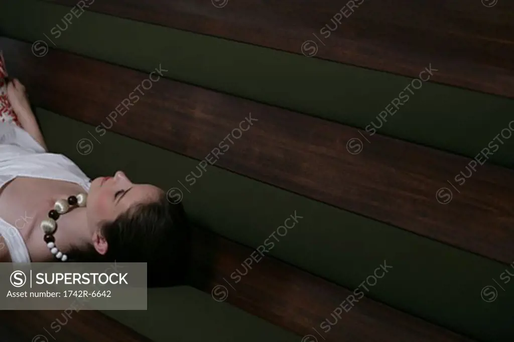 Young woman laying on cafe bench.