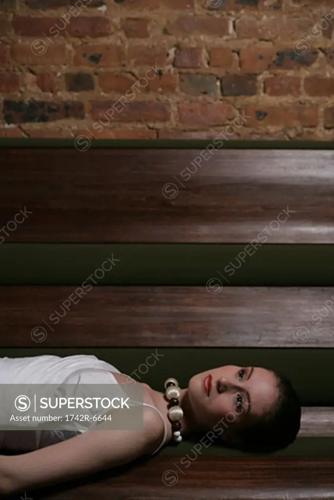 Young stylish woman laying on cafe bench.