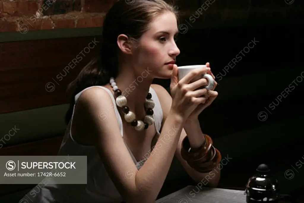 Young stylish woman drinking coffee in cafe.