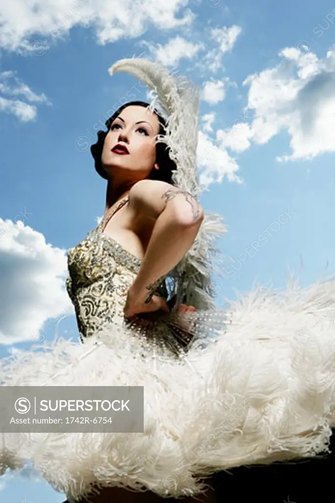 Young sexy woman in feather costume standing outdoors.