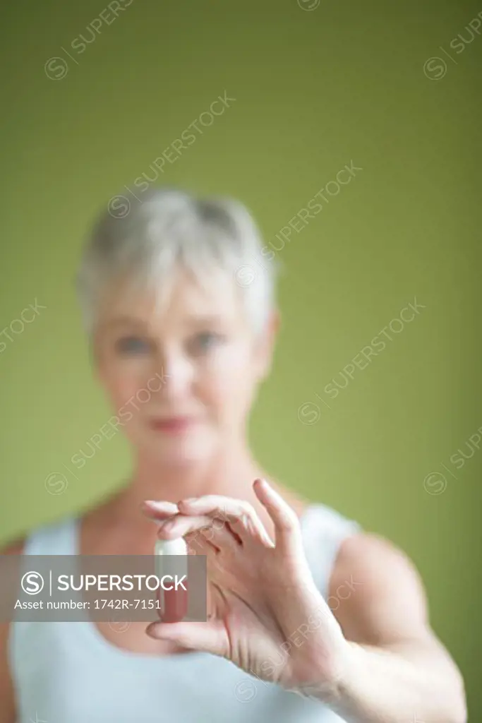 Mature woman holding large pill.