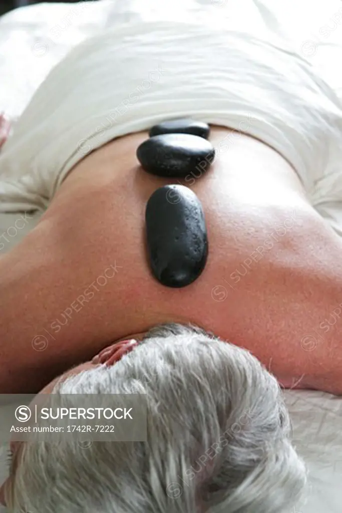 Mature woman getting hot stone massage.