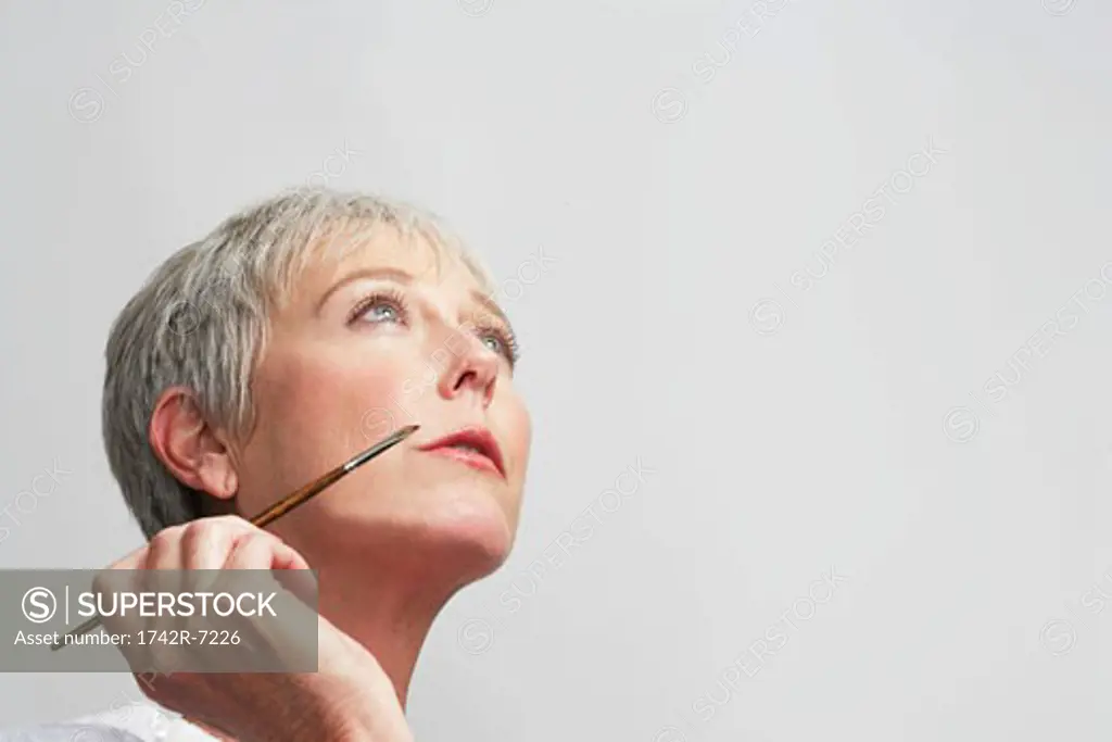 Mature woman holding lipstick brush.