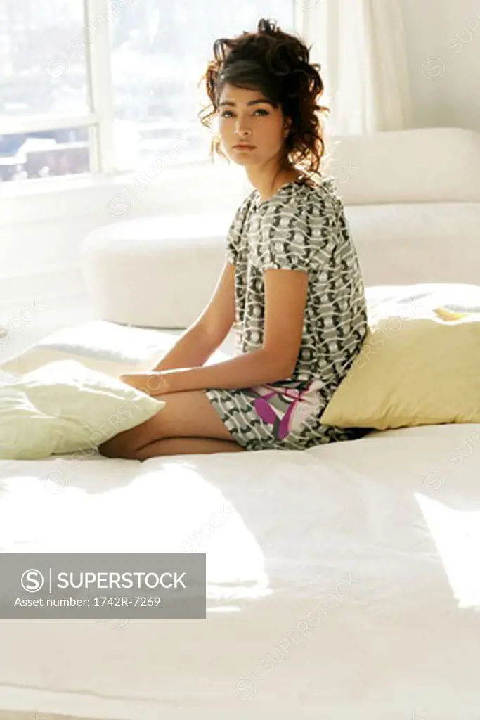 Young stylish woman sitting on bed.