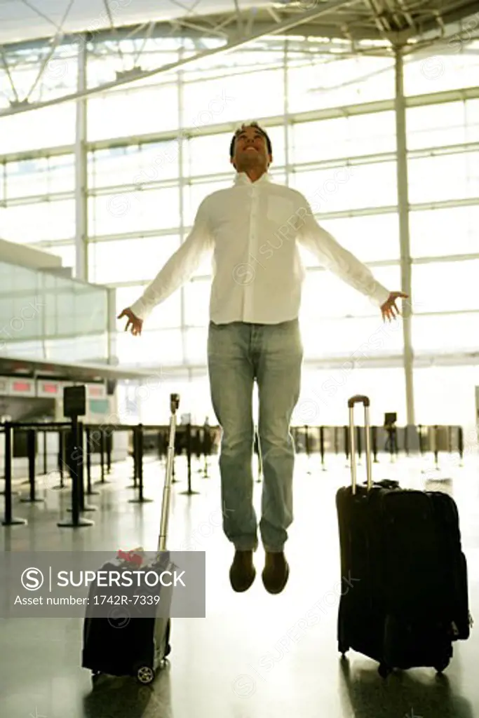 Young man levitating in airport.