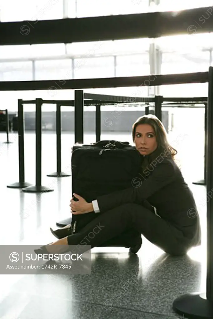 Young businesswoman hugging luggage in airport.