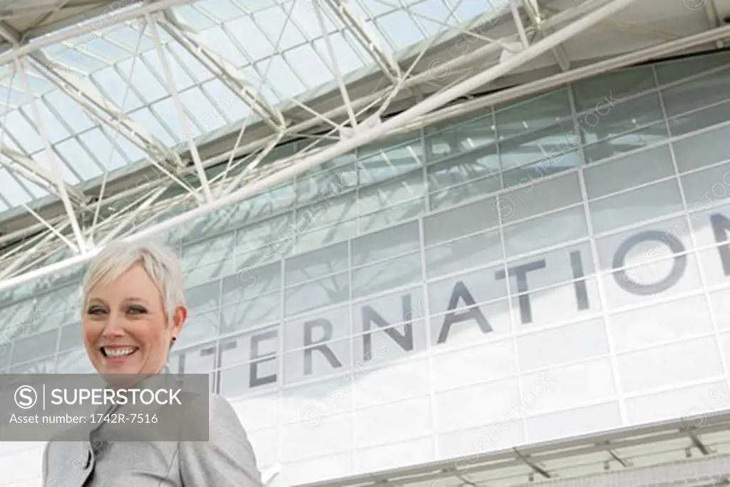 Mature woman standing in front of airport.