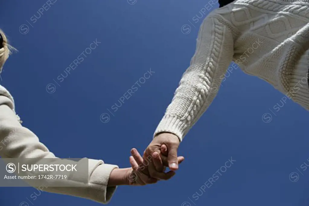 Low angle view of couple holding hands.