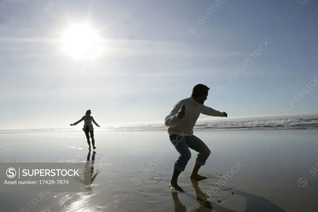 Young couple skipping rocks at beach.