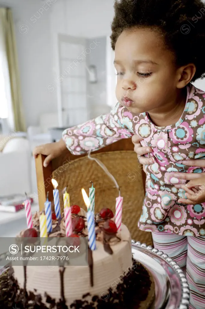 African American child blowing out birthday candles.