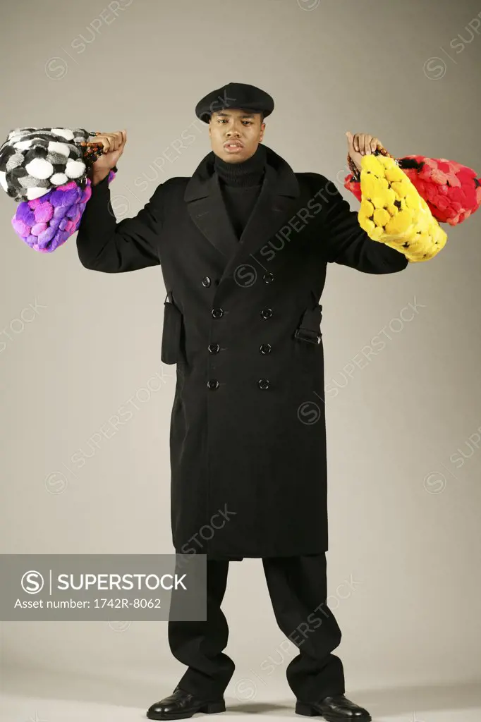 Young African American man holding stylish purses.