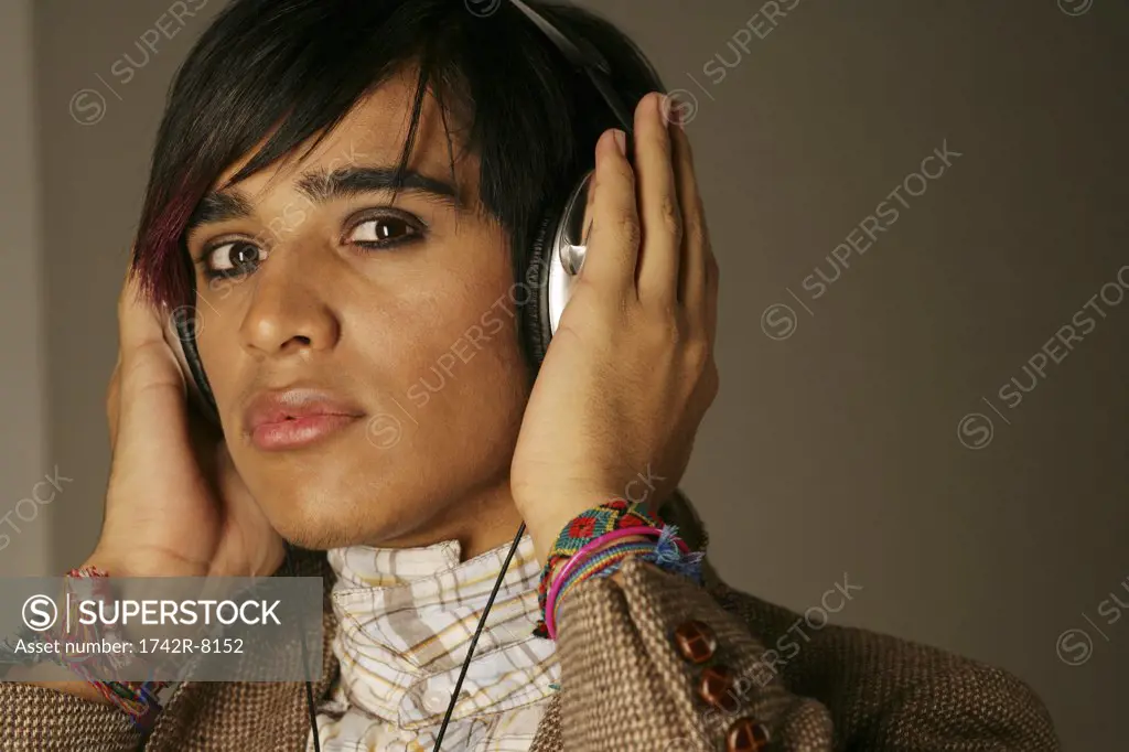 Young man listening to headphones, studio shot.