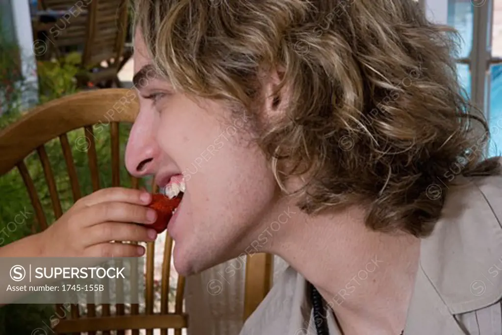 Close-up of a man being fed a strawberry