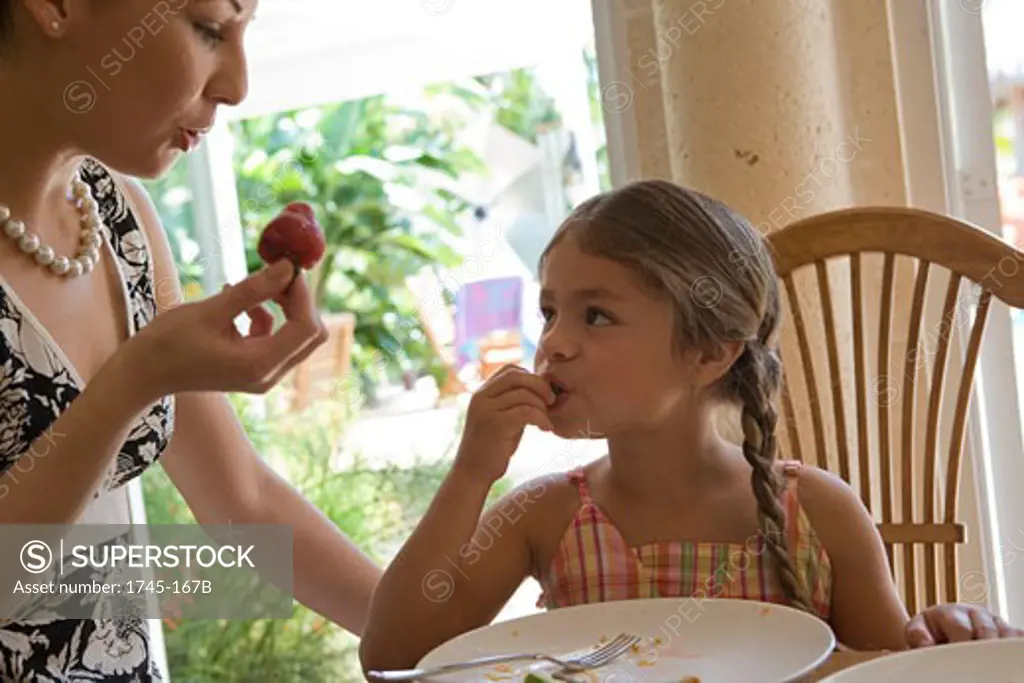 Young woman watching her daughter eat