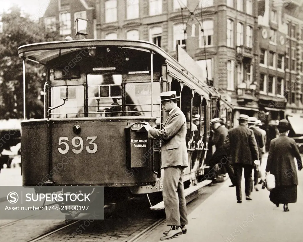Man posting a letter in a post collection box attached to a tram in Amsterdam; Netherlands 1925