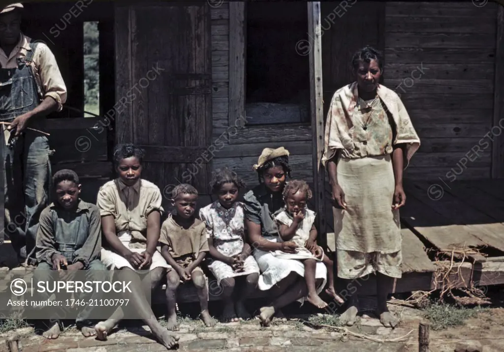 Photograph of a Negro family seated on the porch of a house at the Bayou Bourbeau Plantation, Louisiana. Photographed by Marion Post Wolcott. Dated 1940