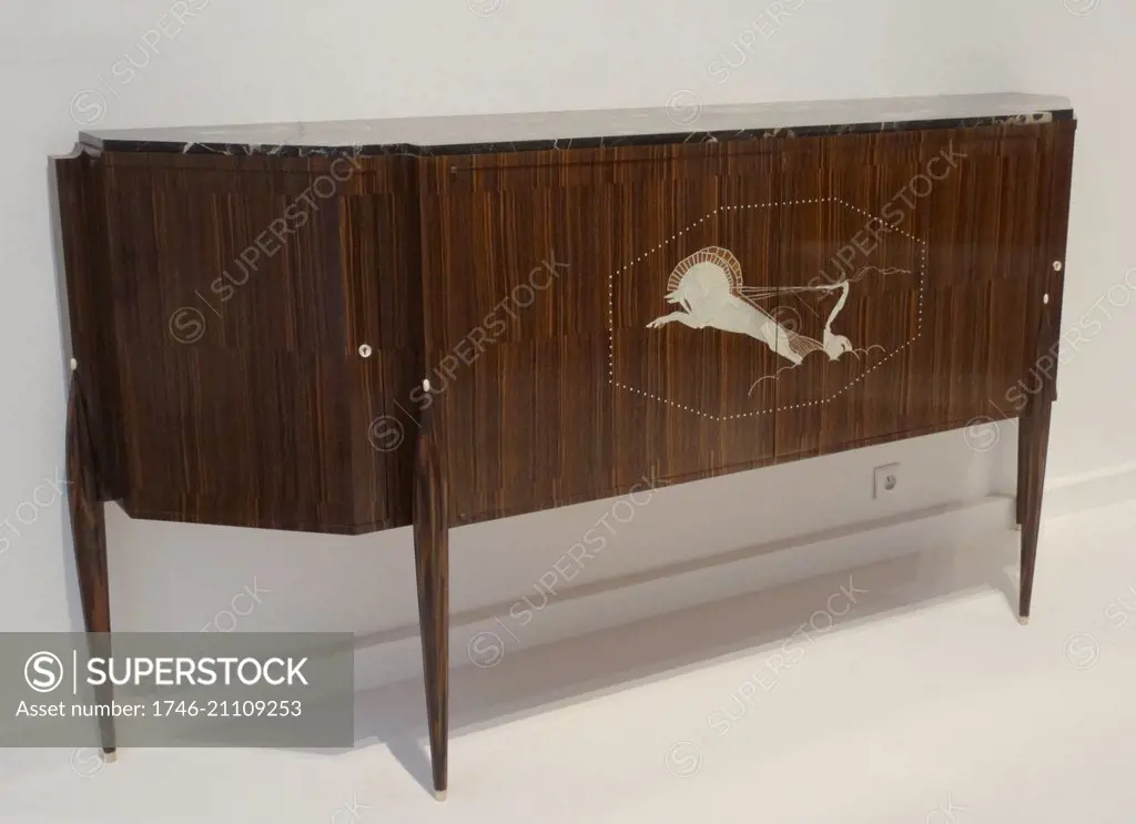Desserte dite meuble au char Sideboard with an ivory inlay 1921. By Jacques-Emile Ruhlmann. mile-Jacques Ruhlmann (28 August 1879 ñ 15 November 1933), his first names often seen reversed as Jacques-mile, was a renowned French designer of furniture and interiors, epitomising for many the glamour of the French Art Deco style of the 1920s.