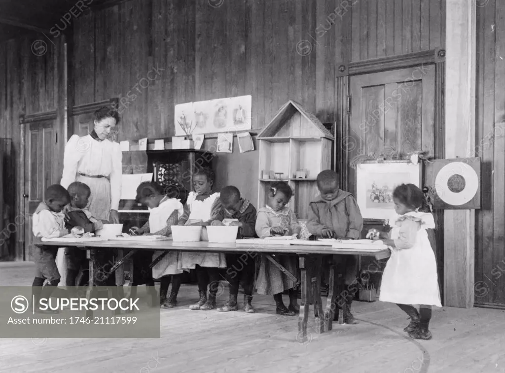 Eight African American children, in kindergarten, learning washing and ironing at Whittier Primary School, Hampton, Virginia 1900.