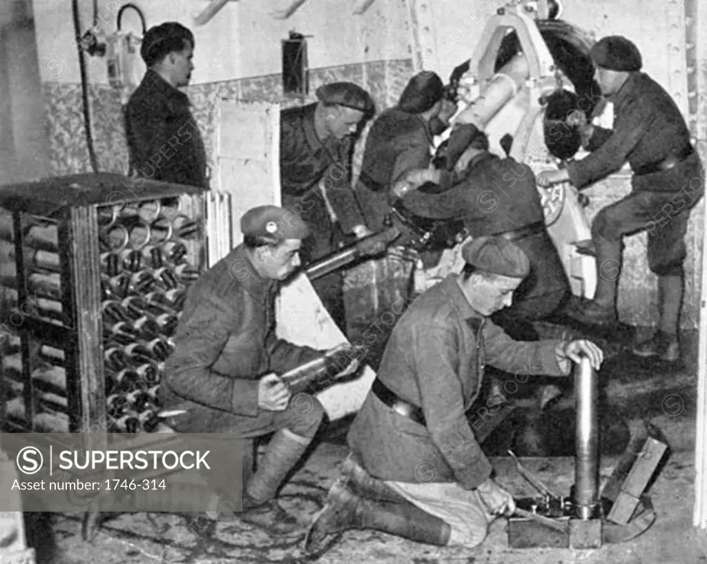 Troops working in one of the underground artillery towers of the Maginot Line defensive installation. Man in foreground is using a time-fuse setter, early 1940, World War II