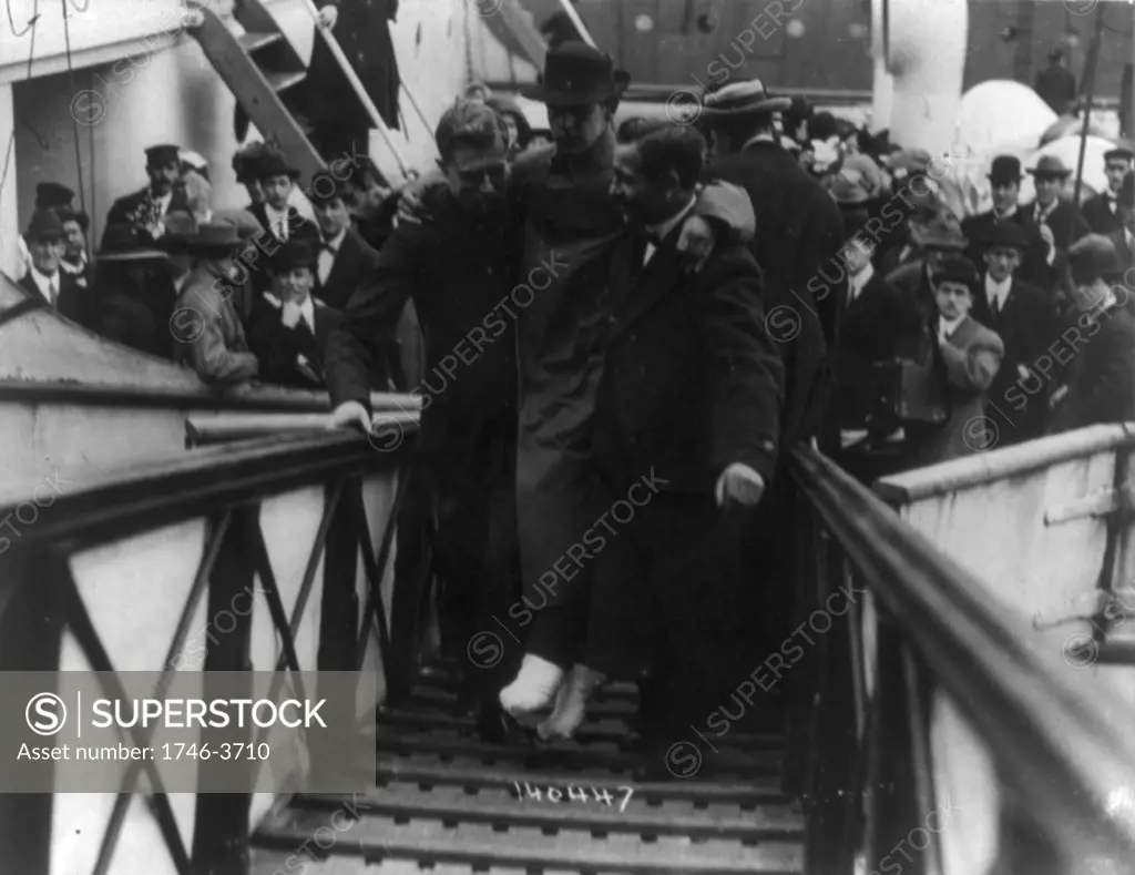 Loss of White Star Line's Olympic-class vessel RMS Titanic which struck an iceberg on 12 April 1912 on her maiden voyage. Surviving wireless operator, Harold Bride, feet bandaged, being carried up gangway, New York. Disaster