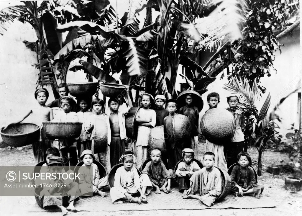 Children with locally made baskets posed under a palm tree, Saigon South Vietnam, c1900. Saigon  was the capital and commercial centre of French colonialism in French Indo-China.