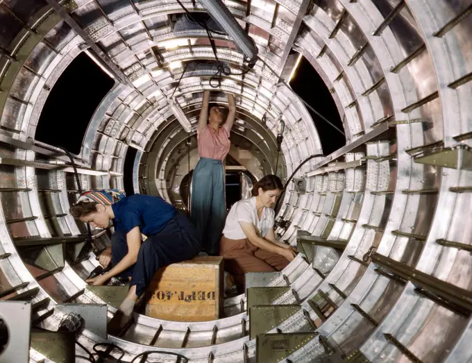 Photograph of female workers installing fixtures and assemblies to a tail fuselage section of a B-17F bomber at the Douglas Aircraft Company, Long Beach, Calif. Better known as the 'Flying Fortress,' the B-17F is a later model of the B-17 which distinguished itself in action in the South Pacific, over Germany and elsewhere. It is a long range, high altitude heavy bomber, with a crew of seven to nine men, and with armament sufficient to defend itself on daylight missions. Dated 1942