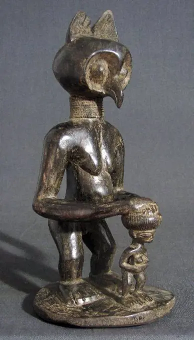 Tribal art: Owl-headed figure protecting a small child. Wood carving, Chokwe tribe, Angola, Africa. The owl as a symbol of wisdom.