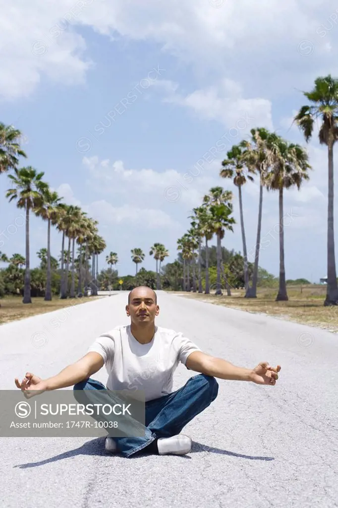 Man sitting in the middle of the road in lotus position