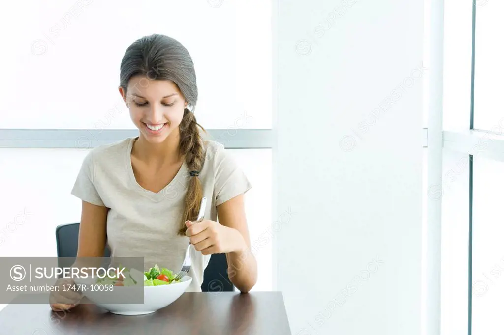 Teen girl eating salad, smiling