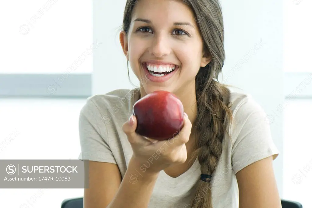 Teen girl holding apple, smiling, portrait