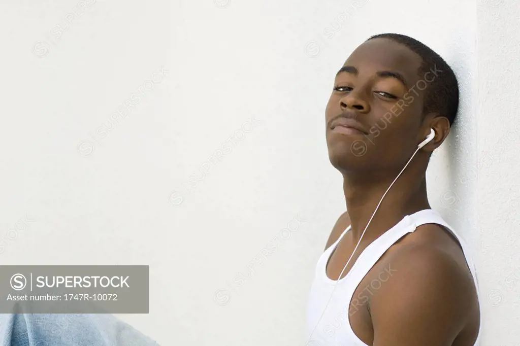 Teen boy listening to earphones, looking at camera