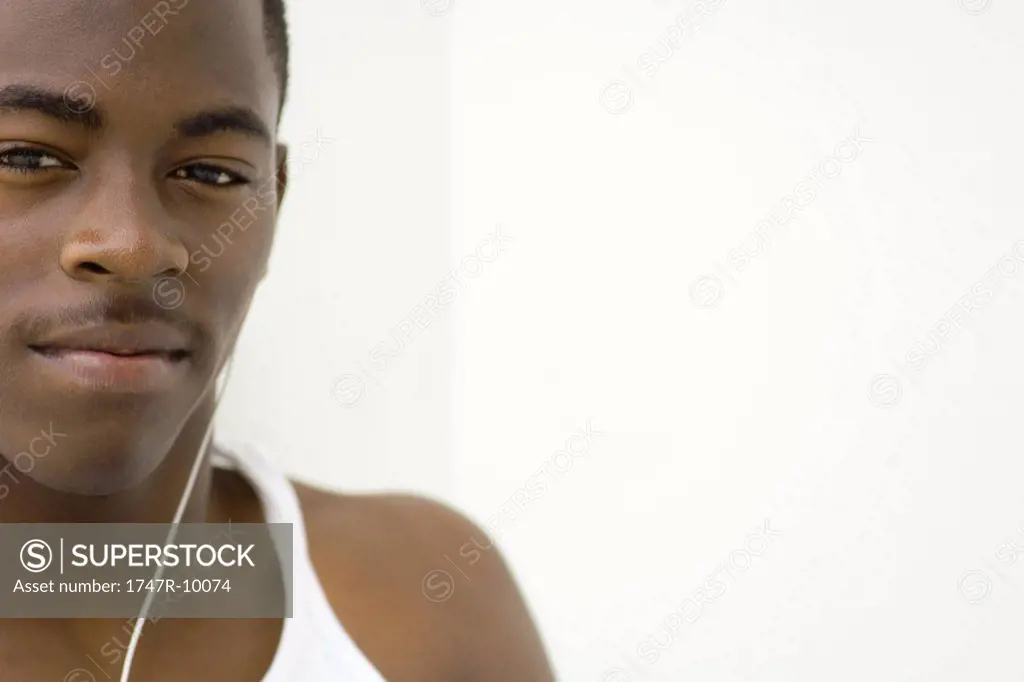 Teen boy listening to earphones, portrait, cropped