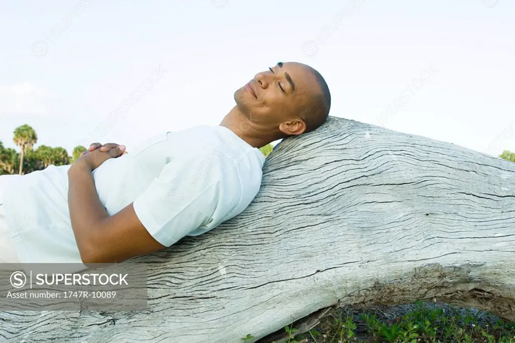 Man lying on back on wood surface, eyes closed, smiling