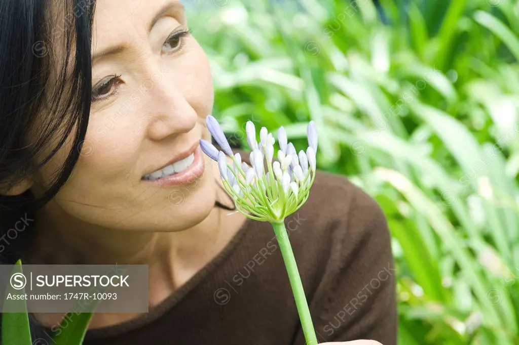 Woman smelling African lily, smiling, looking away