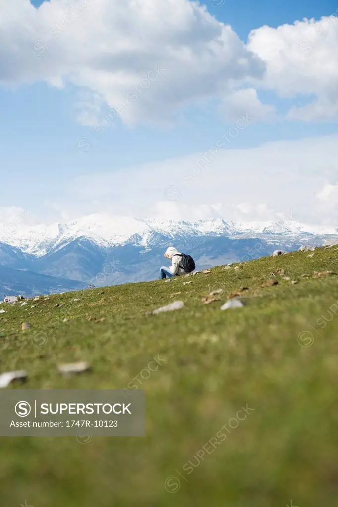 Hiker sitting in mountain landscape