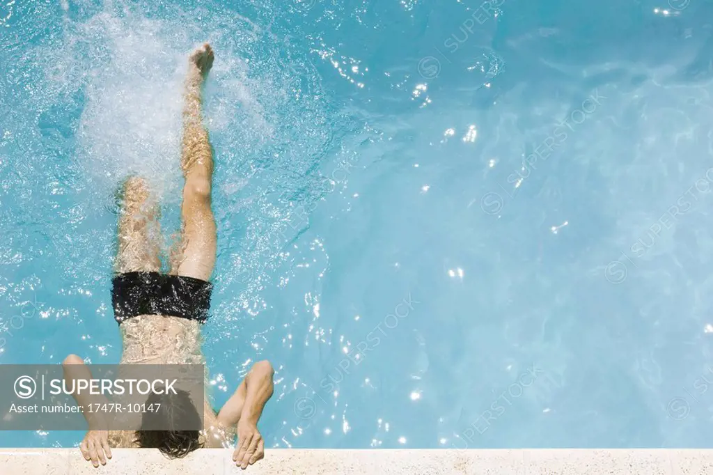 Man holding on to edge of swimming pool, kicking legs, high angle view