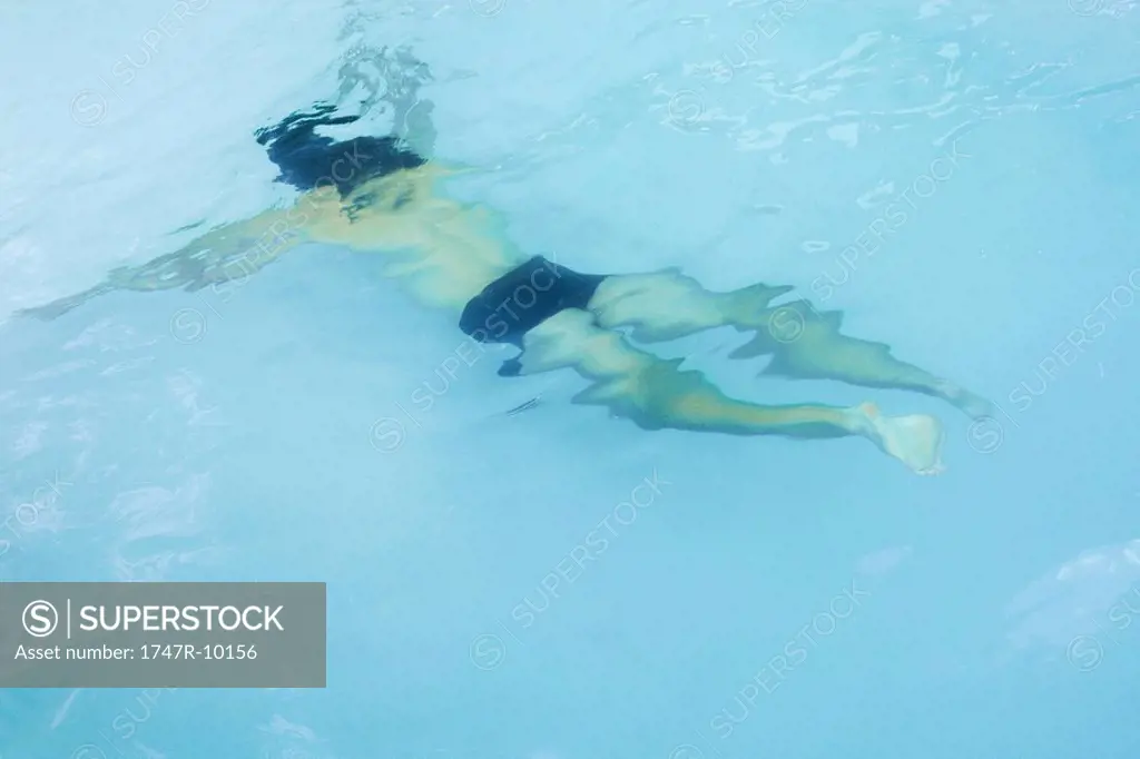 Man swimming underwater in pool, high angle view