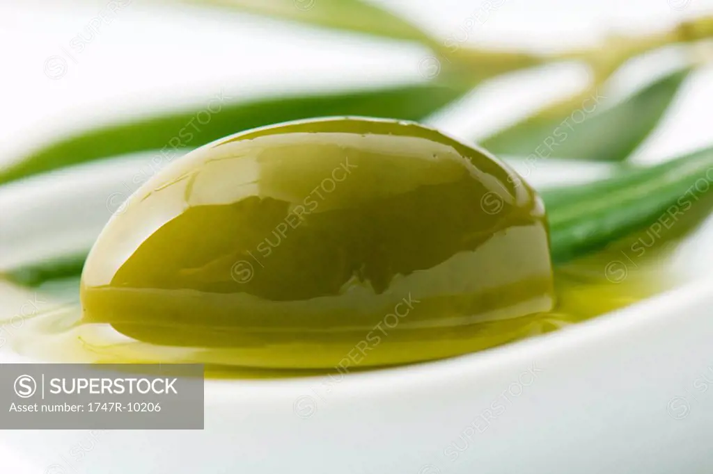 Green olive and oil in dish, close-up