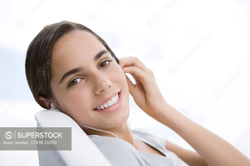 Female listening to earphones, smiling over shoulder at camera