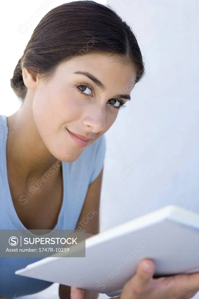 Female holding book, smiling at camera